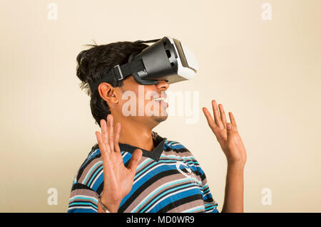 Junge erstaunt schaut in eine VR-Brille und gestikulierte wild mit den Händen Stockfoto