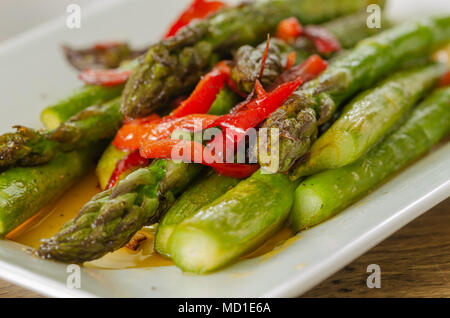 Red Pepper sauteed grüner Spargel als Salat auf dem weißen Teller serviert. Stockfoto