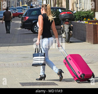 Junge Frau geht mit Gepäck auf der Straße Stockfoto