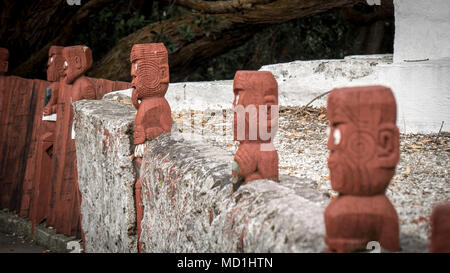 Traditionelle Maori-Schnitzereien, Holzskulpturen in einer Reihe, aufgenommen in Rotorua, Neuseeland. Stockfoto