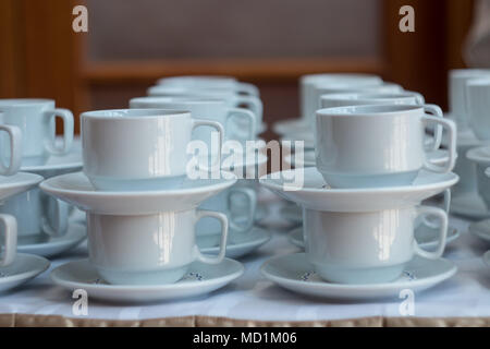 Weiße Tassen für Tee auf dem Tisch stapeln mit Platten für Kaffee - Pause. Catering Konzept. Stockfoto