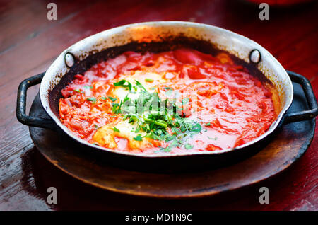 Shakshuka. Traditionelle jüdische Speisen und nahöstliche Küche Rezept. Spiegelei, Tomaten, Paprika und Petersilie in der Pfanne. Close Up, selektive Schwerpunkte Stockfoto