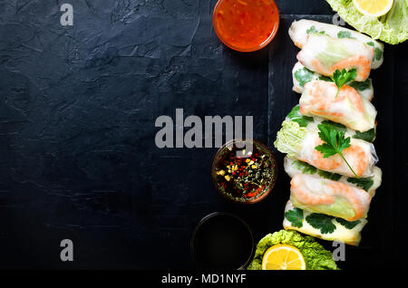 Frisch Vietnamesisch, Asiatisch, Chinesisch essen Rahmen auf Schwarz konkreten Hintergrund. Frühlingsrollen Reispapier, Salat, Salat, Nudeln, Nudeln, Garnelen, Fische Stockfoto