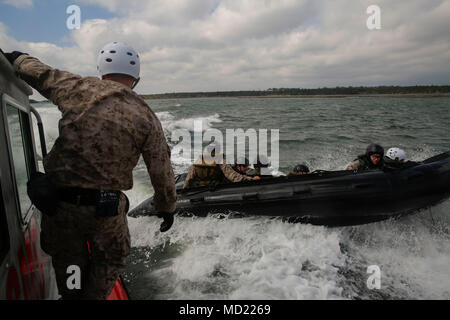 Kapitän Michael Siani, der Assistant Offizier, Expeditionary Operations Training Gruppe II Marine Expeditionary Force, hängt an der Seite eines Safety Boot nach der Marines, die neben Bohrer Bewertung Während der Steuermann Kurs in Camp Lejeune, N.C., 7. März 2018. Die Marines durchgeführt Neben Bohrer als Teil ihrer Steuermann Qualifikationen Kurs die Fähigkeit von Fahrwerk und Personal vom Schiff mit einer Bekämpfung Gummi Streifzüge Handwerk eine taktische Szenario zu Schiff besser zu stellen. Einheiten, die an der Schulung nahmen inbegriffen Expeditionary Operations Training Grou Stockfoto