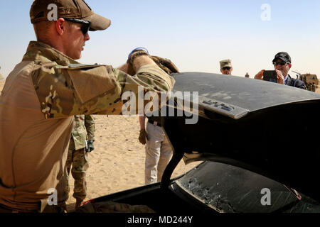 CAMP BUEHRING, Kuwait - Cpl. Jon Bradshaw der 797 . Explosive Verpackungsverordnung Company erklärt die Dynamik der Sprengladungen zu Lawrence R. Silverman, der Botschafter der USA zu den Staat Kuwait, zu einem Abriss Bereich März 8, 2018. Bradshaw war die Teilnahme an der Abbruch der Ausbildung, wo die EOD-Unternehmen über 80 155 mm Artillerie Umläufe mit Sprengstoff verpackt zur Detonation gebracht, um ihre Fähigkeiten zu verbessern und ihre Fähigkeiten an den Botschafter der USA demonstrieren, von dem Staat Kuwait. Die Botschaft zur Verfügung gestellt Vier gepanzerte Fahrzeuge für die Entsorgung in Übereinstimmung mit der Abteilung der Staatlichen Vorschriften Stockfoto