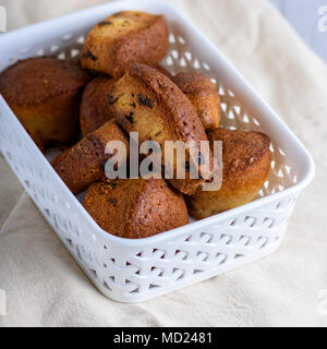 Kleine runde gebackenen Muffins mit trockenem Obst und Rosinen in einem weißen Weidenkorb, Ansicht von oben Stockfoto