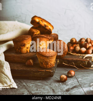 Kleine runde gebackenen Muffins mit trockenen Früchten und Trauben auf einem braunen Holzbrett, vintage Toning Stockfoto