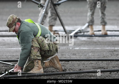 Operation Patriot Bandolier ist eine Logistikmission der United States Army, die die Streitkräfte der Army Reserve, der National Guard und Active Component umfasst, um Material und Munition innerhalb der Vereinigten Staaten zu transportieren. Am 2. März 2018 baut ein Soldat der US-Armee ein mobiles Wartungszelt am Military Ocean Terminal Concord, Kalifornien. Das Archivbild dokumentiert Terminaloperationen, die strategische Sealift-Aktivitäten unterstützen. Stockfoto