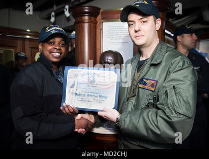 NORFOLK, Virginia (Mar. 16, 2018) - der Luftfahrt Bootsmann Mate (Ausrüstung) Airman Abriel Thomas, von Groesback, Texas, zu USS Gerald R. Ford's (CVN 78) Luft Abteilung zugewiesen, erhält ein Zertifikat, das der Entlastung von Leutnant Adam Boyd während Ihrer reenlistment Zeremonie. (U.S. Marine Foto von Mass Communication Specialist 3. Klasse Ryan Carter) Stockfoto