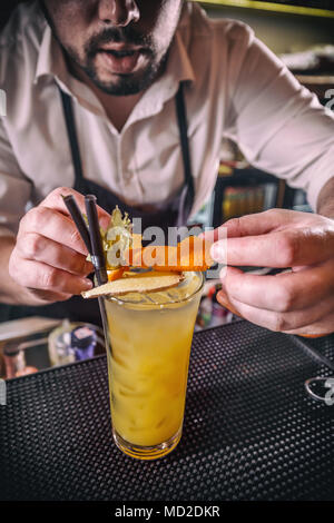 Barkeeper verziert alkoholfreien Cocktail mit Orangenschale Stockfoto