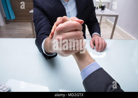 Close-up von zwei Geschäftsmänner im Armdrücken auf dem Schreibtisch am Arbeitsplatz konkurrieren Stockfoto