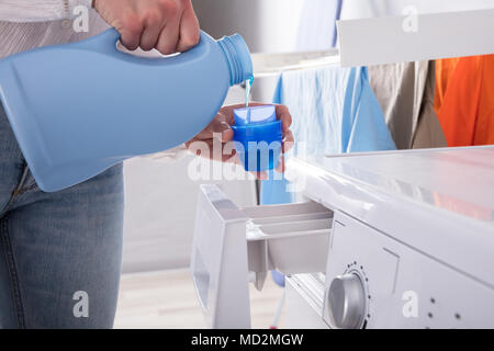 Nahaufnahme der Hand Gießen einer Person Waschmittel im Deckel Stockfoto