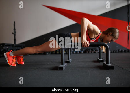 Bild Seite der jungen Frau zu tun horizontale Push-ups mit Bars Stockfoto