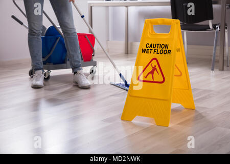 In der Nähe von Yellow Wet Floor Warnschild in der Nähe von Hausmeister Reinigung Büro Stockfoto