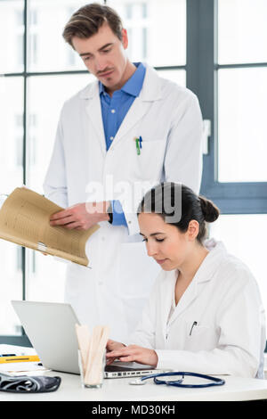 Arzt und Apotheker Prüfen von Informationen auf einem Laptop in einem Krankenhaus Stockfoto