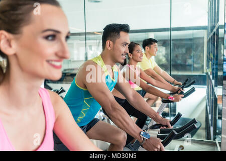 Schön freundlich lächelnden Frau während des Trainings an Indoor Cycling Group Klasse Stockfoto