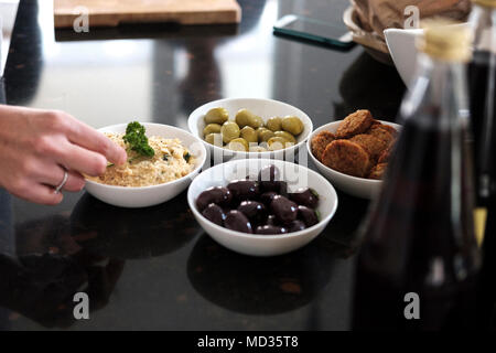 Hummus Klassische, schwarze und grüne Oliven und Falafel, Gruppe von Freunden beiläufig Snacking auf eine Auswahl von Lebensmitteln beim Lachen und sich zu amüsieren. Stockfoto