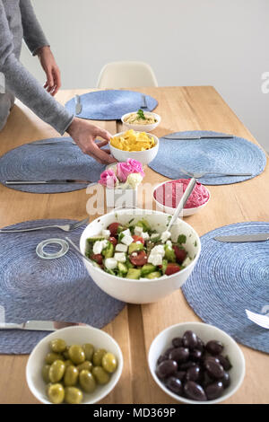 Einrichten der Tabelle für vegtarian Mahlzeit - griechischer Salat, grüne und schwarze Oliven und Rote Beete Hummus - selektive Fokus Stockfoto