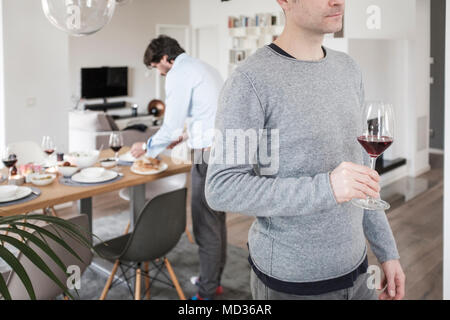 Freunde einrichten Tisch für das Mittagessen. Gruppe von Freunden beiläufig Snacking auf eine Auswahl von Lebensmitteln beim Lachen und sich zu amüsieren. Stockfoto