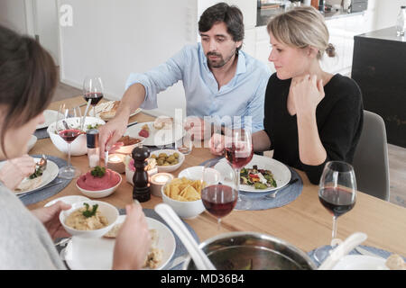 Vegetarisches Mittagessen. Gruppe von Freunden beiläufig Snacking auf eine Auswahl von Lebensmitteln beim Lachen und sich zu amüsieren. Stockfoto