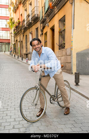 Junge glücklich attraktive latin Mann in casual trendy Kleidung lächelt fröhlich Reiten auf vintage Coole Retro Fahrrad in moderner, stilvoller Lifestyle urban Styl Stockfoto