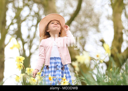 Vier Jahre altes Mädchen sitzt dargestellt unter Frühling Narzissen in einem Park GROSSBRITANNIEN Stockfoto