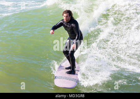 Bournemouth, Dorset, Großbritannien. 18. April 2018. UK Wetter: große Wellen bieten ideale Surfbedingungen am Strand von Bournemouth am heißesten Tag des Jahres so weit. In Aktion auf Surf Board einer Welle Surfer. Stockfoto