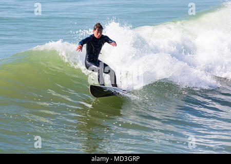 Bournemouth, Dorset, Großbritannien. 18. April 2018. UK Wetter: große Wellen bieten ideale Surfbedingungen am Strand von Bournemouth am heißesten Tag des Jahres so weit. In Aktion auf Surf Board einer Welle Surfer. Stockfoto