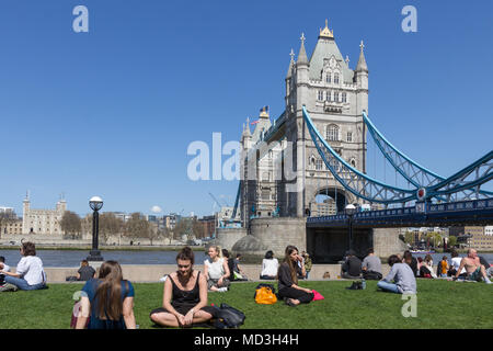 London, Großbritannien. 18 Apr, 2018. Die Menschen in der Sonne entlang der Themse, die Tower Bridge im Hintergrund, auf einem der heißesten Tage des Jahres bisher. Das warme Wetter wird voraussichtlich für den Rest der Woche. Credit: Milton Cogheil/Alamy leben Nachrichten Stockfoto