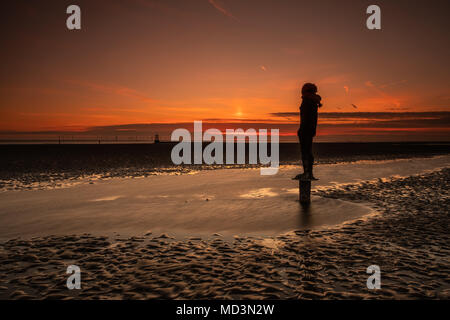 Crosby, UK. 18. April 2018. Der wärmste Tag des Jahres, so weit, kommt zu einem Ende mit einem bunten Sonnenuntergang als einer der Statuen Uhren Antony Gormley" an einen anderen Ort "Am Crosby Beach im Nordwesten von England am Mittwoch, den 18. April 2018. © Christopher Middleton/Alamy leben Nachrichten Stockfoto