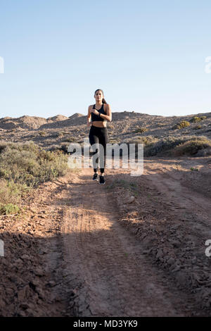 Junge Läuferin entlang Feldweg in ariden Landschaft läuft, Las Palmas, Kanarische Inseln, Spanien Stockfoto