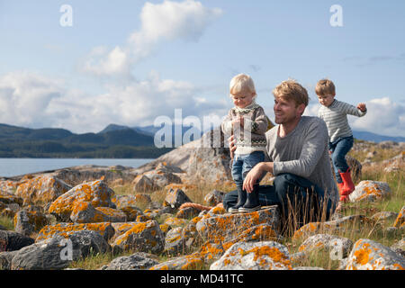 Mann mit Söhne spielen durch Fjord, Aure, Mehr og Romsdal, Norwegen Stockfoto