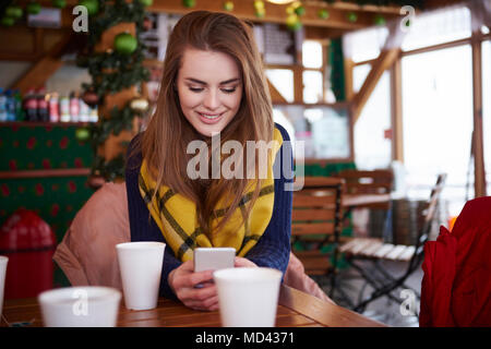Junge Frau über SMS auf Handy lächeln Stockfoto