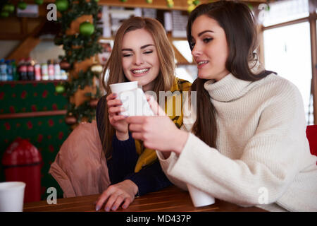 Junge Frauen lächelnd über SMS auf Handy Stockfoto