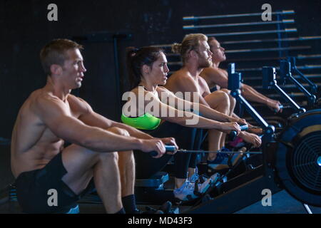 Gruppe von Menschen trainieren im Fitnessraum, mit Rudergeräte Stockfoto