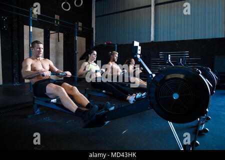 Gruppe von Menschen trainieren im Fitnessraum, mit Rudergeräte Stockfoto