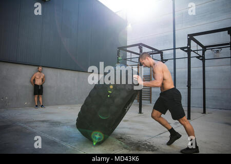 Mann, das trainieren im Fitnessraum, Hebezeuge Reifen Stockfoto