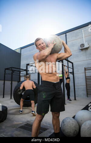 Vier Leute trainieren im Fitnessraum, Mann im Vordergrund, den Einsatz von Atlas Stein Stockfoto