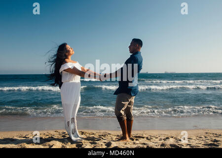 Couple standing on beach, holding hands, face to face, Seal Beach, California, USA Stockfoto
