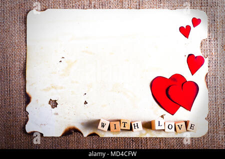 Alte vintage Blatt Papier, zwei rote Herzen, Wörter mit Liebe auf den Würfel auf Sackleinen, Sack Hintergrund. Retro Design Effekte. Stockfoto