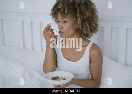 Junge Frau beim Frühstück im Bett Stockfoto