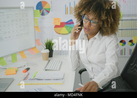 Nachdenkliche Frau im Büro am Telefon sprechen Stockfoto