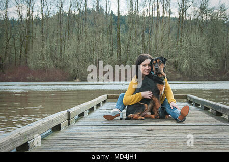 Eine Frau und ihr Hund auf einem Dock in Oregon sitzen. Stockfoto