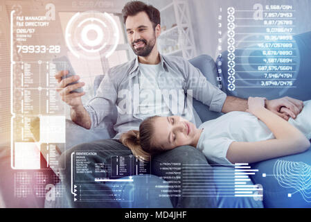 Junge Frau schlafen, während ihr Freund im Internet surfen. Stockfoto