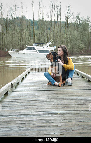 Eine Frau und ihr Hund auf einem Dock in Oregon sitzen. Stockfoto