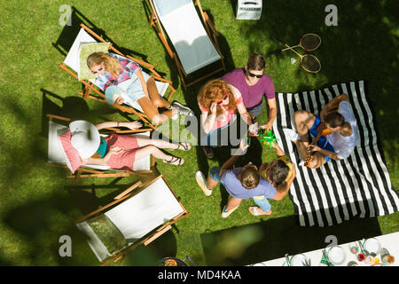 Blick von oben auf die Gruppe der Freunde genießen Sommer Garden Party in der Landschaft, sitzen auf den Liegestühlen, Reden und Liegewiese umgeben von Natur Stockfoto