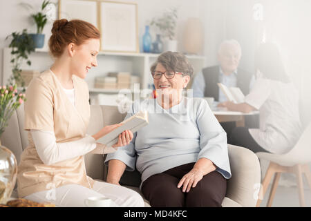 Freiwillige Lektüre von Büchern an die Rentner in einem Pflegeheim Stockfoto