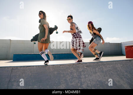 Gruppe von weiblichen Freunde genießen Skate Park. Fröhlicher junger Frauen laufen über Skateboard Rampe bei Skate Park. Stockfoto