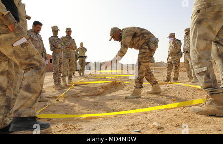 Ein irakischer Bundesgrenzschutz Force Trainer korrekte Techniken begraben zu identifizieren Sprengkörper auf irakische Soldaten im Camp Al Asad, Irak, 20. März 2018 improvisiert. Der Lehrplan erweiterte Kapazitäten Standorte umfasst: Führung, Ethik und Recht des Krieges Schulungen und Anweisungen. Zusätzlich werden die rekruten sind land Navigation gelehrt, medizinische Grundausbildung, Infanterie Fähigkeiten und kleine Einheit Taktik. (U.S. Armee Foto von SPC. Zakia Grau) Stockfoto