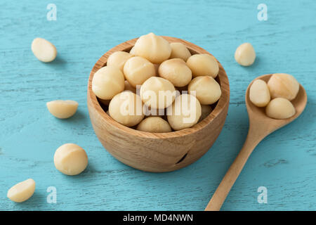 Macadamia Nüsse in der Schale auf der blauen Holztisch Stockfoto